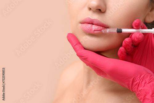 Young woman receiving lip injection against color background  closeup
