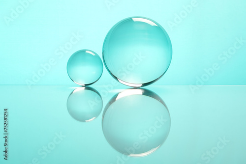 Transparent glass balls on mirror surface against turquoise background