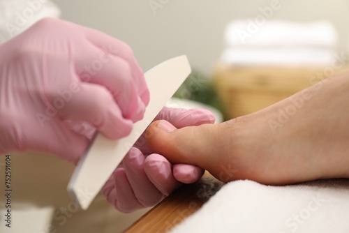 Professional pedicurist filing client s toenails in beauty salon  closeup