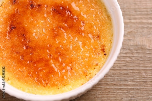 Delicious creme brulee in bowl on wooden table, top view