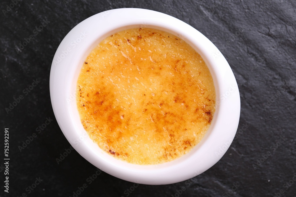 Delicious creme brulee in bowl on dark gray textured table, top view Delicious creme brulee in bowl on dark gray textured table, top view