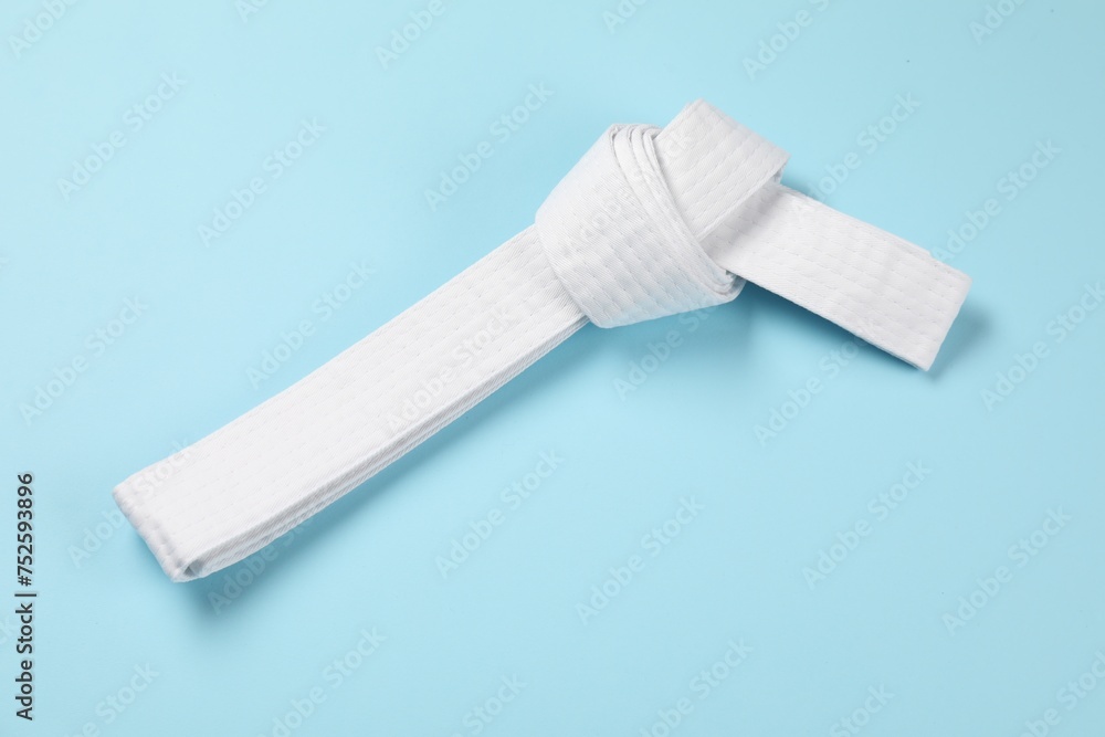 Obraz premium White karate belt on light blue background, top view