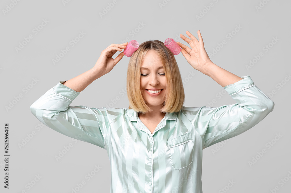 Beautiful young woman with bob hairstyle and hair curlers on grey background Beautiful young woman with bob hairstyle and hair curlers on grey background