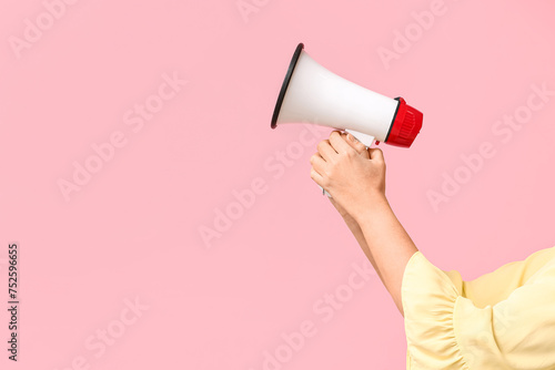 Female hands with megaphone on pink background