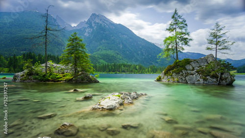 Hintersee near Ramsau, Berchtesgaden, Bavaria, Germany. Famous view of rocks with coniferous trees surrounded by water with mountains in the background. Smooth water surface. photo