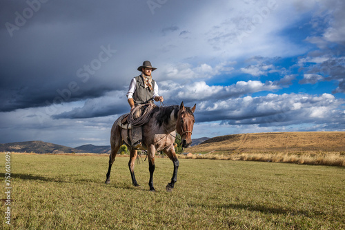 Cowboy riding a roan cow ranch horse with dark storm clouds © Terri Cage 
