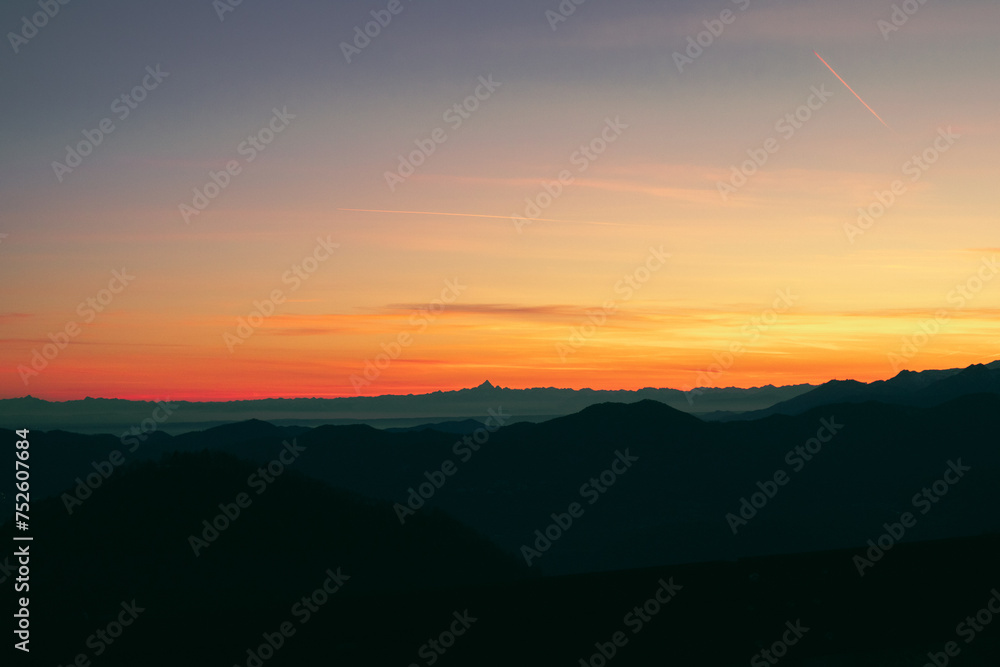 Staring at the horizon, orange afterglow. Suggestive view of the Alps, with Monviso mountain stands out, from Mottarone mountain (Omegna side) - Piedmont - Italy.