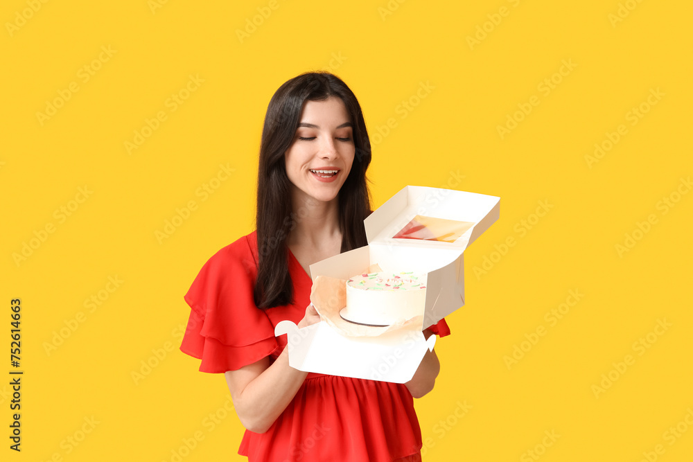 Beautiful young woman holding box with sweet bento cake on yellow background. International Women's Day Beautiful young woman holding box with sweet bento cake on yellow background. International Women's Day