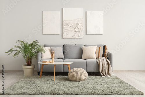 Interior of modern living room with cozy sofa, pictures and coffee table photo