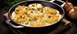 A pan filled with tender potatoes cooked in a creamy cheese gratin, topped with fresh parsley for added flavor and color. The golden-brown cheese bubbles on top of the perfectly cooked potatoes