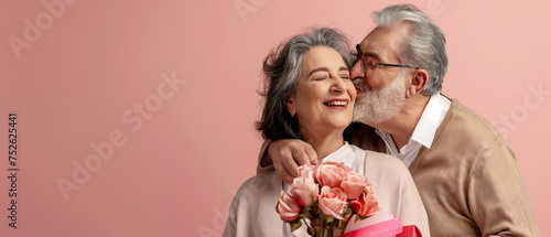 Senior couple hugging and kissing holding a rose bouquet against pink background. Generative AI