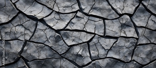 A black and white photograph showcasing the intricate patterns of a cracked stone surface. The details of the cracks create a visually interesting texture, highlighting the natural weathering process photo
