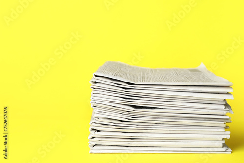 Stack of newspapers on yellow background. Journalist's work