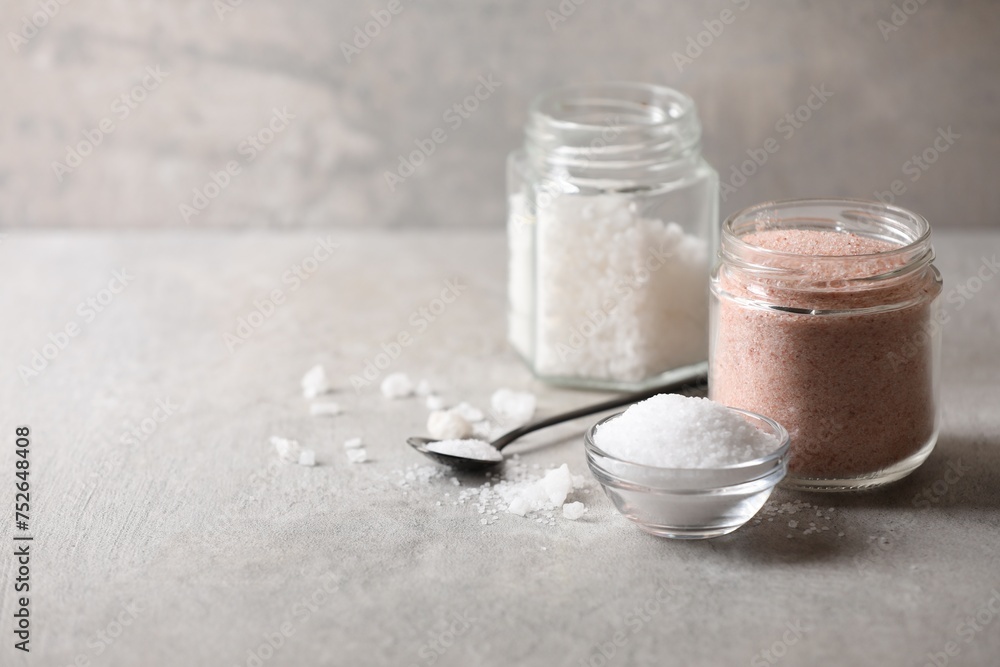 Different natural salt on grey textured table, space for text Different natural salt on grey textured table, space for text