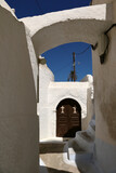 A church door in the narrow alleyways of the village of Megalochori on the island of Santorini with the traditional lime-washed buildings.