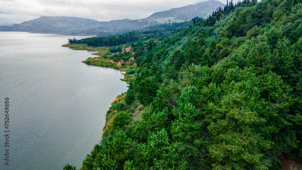 Scenic view of serene Tominé Reservoir, Guatavita, surrounded by lush greenery under a cloudy sky Scenic view of serene Tominé Reservoir, Guatavita, surrounded by lush greenery under a cloudy sky