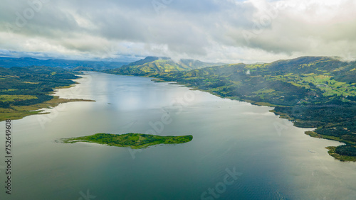 Aerial view of tranquil Tomine Reservoir, lush greenery under a cloudy sky in Guatavita, Cundinamarca, Colombia