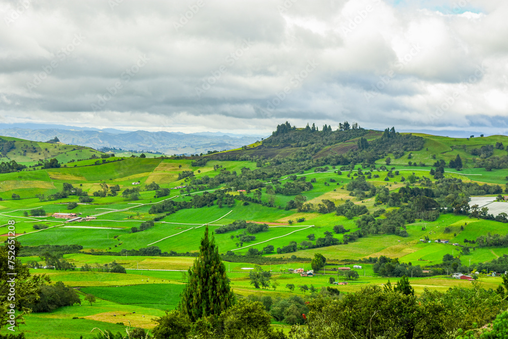 Fototapeta premium Breathtaking landscape of Guatavita, Cundinamarca with vibrant green fields and cloudy sky