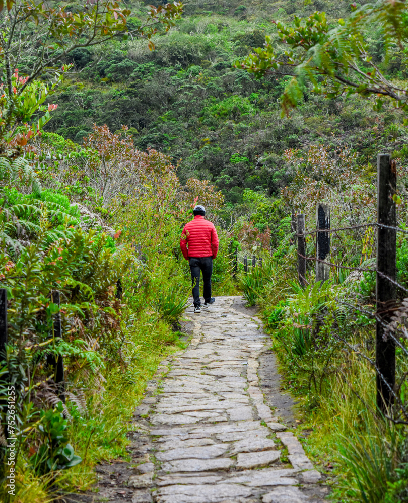 Person in red jacket walking on a stone path at Laguna de Guatavita, Cundinamarca, Colombia