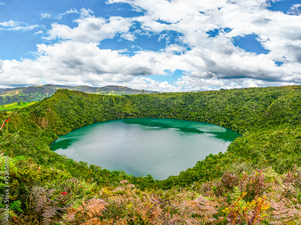 Obraz premium Breathtaking view of serene Laguna de Guatavita, lush greenery under vibrant sky in Guatavita, Cundinamarca