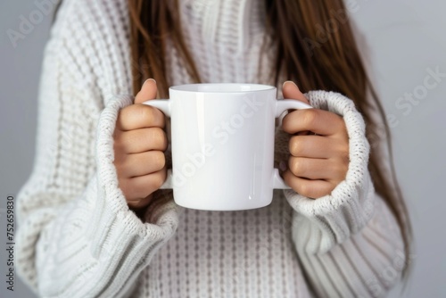 Close-up of warm hands clutching a steamy coffee mug, wrapped in a knitted white sweater, suggesting comfort on a cold day.