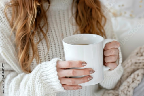 Close-up of warm hands clutching a steamy coffee mug, wrapped in a knitted white sweater, suggesting comfort on a cold day.nail beautiful