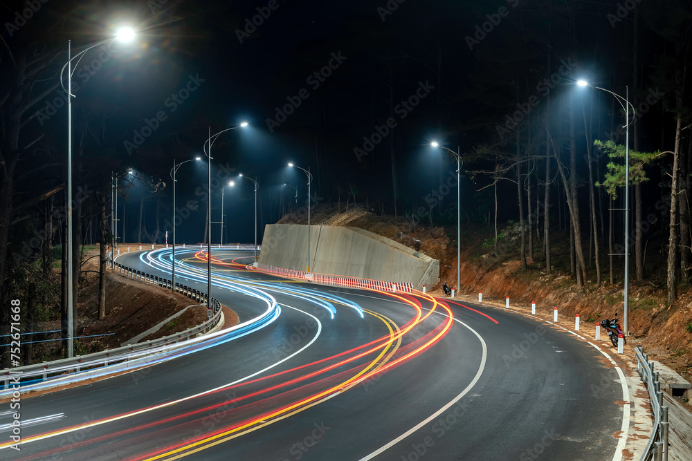 Night scene at the newly widened curved pass in Da Lat, Vietnam illuminated by the headlights of passing cars on a dark night to help traffic flow more smoothly when tourists come here