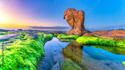 Landscape of rocky beach at sunrise with moss and pebbles on Co Thach beach, a famous beach in Binh Thuan province, central Vietnam photo