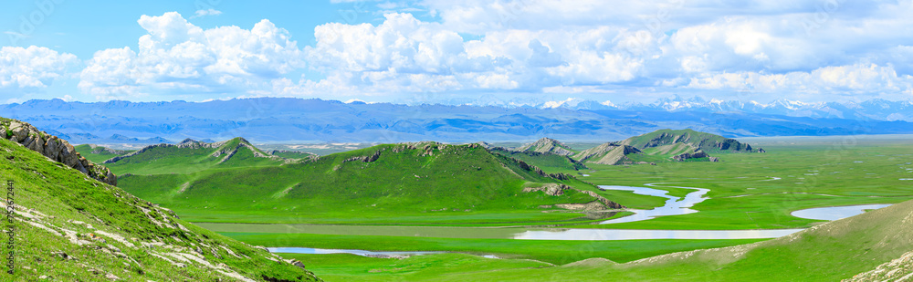 Curved river and green grassland with mountain natural landscape in Xinjiang. Panoramic view.