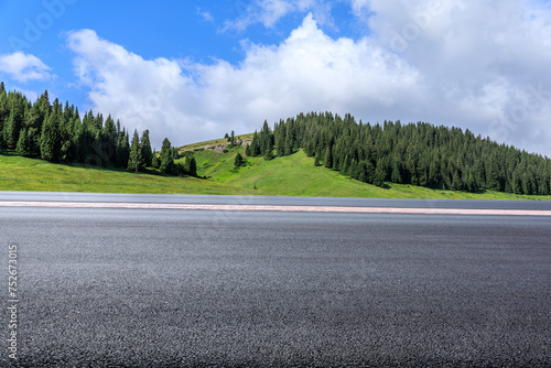 Asphalt highway road and green forest with mountain nature landscape under blue sky