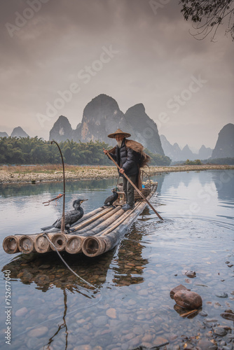 Sailing peacefully across a river, Guilin cormorant fishermen set out on river