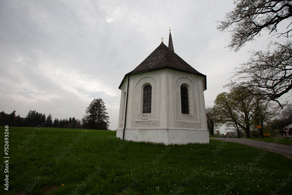 A small white building perched on a vibrant green field, creating a picturesque and tranquil scene. A small white building perched on a vibrant green field, creating a picturesque and tranquil scene.