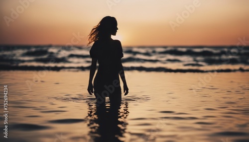 view of silhouette of a girl standing in the water on a beach as the sun goes down image background