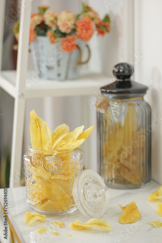 banana chips in a jar with crumbs and blurred background