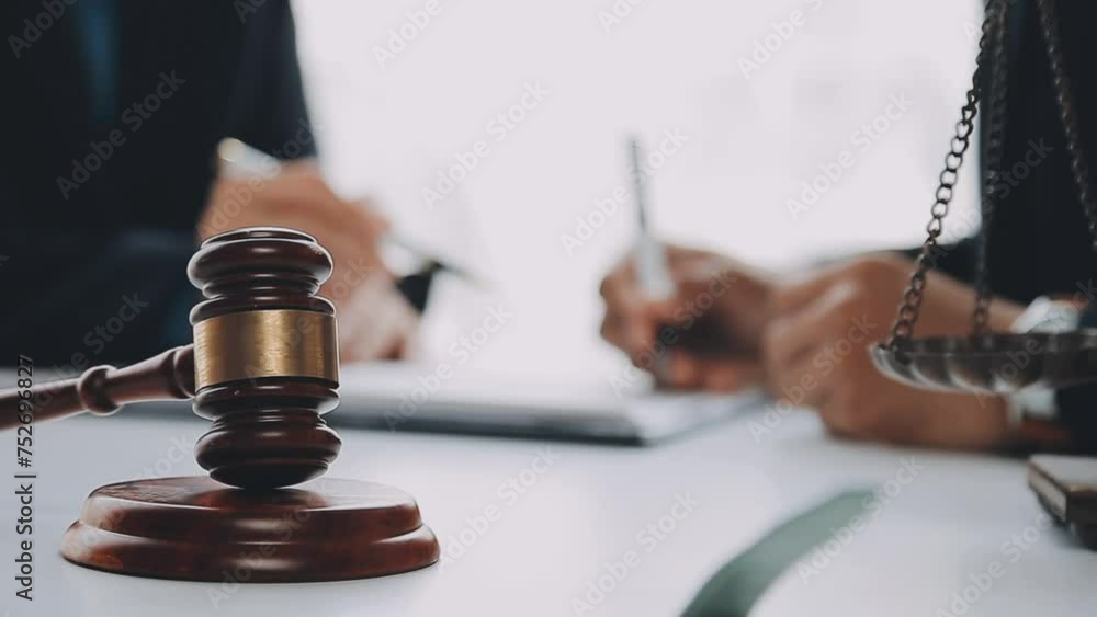 Justice and Law concept. Legal counsel presents to the client a signed contract with gavel and legal law or legal having team meeting at law firm in background Justice and Law concept. Legal counsel presents to the client a signed contract with gavel and legal law or legal having team meeting at law firm in background