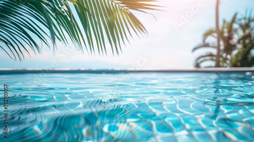 Palm fronds overhanging a calm blue swimming pool in a tropical setting.