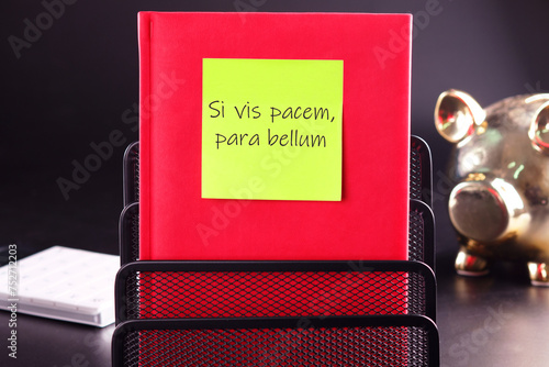 Si vis pacem, para bellum. Latin phrase meaning If you want peace, prepare for the war. on a yellow sticker glued to a red notebook photo