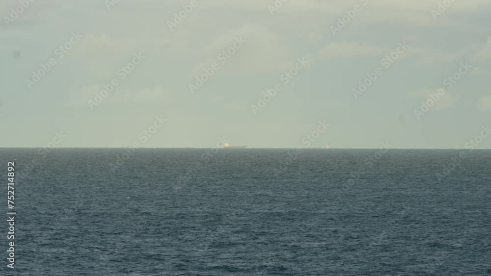 A Cargo Ship Seen in the Distance on the Open Ocean - Wide Shot A Cargo Ship Seen in the Distance on the Open Ocean - Wide Shot