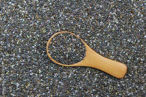 Chia seeds in a wooden spoon on a background of chia seeds