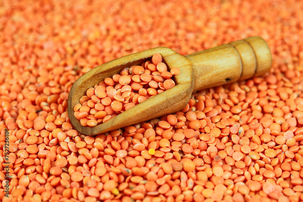 Red lentils in a wooden scoop on a background of red lentils Red lentils in a wooden scoop on a background of red lentils