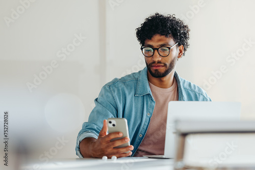 Foto Young businessman using a smartphone to read a text message in office