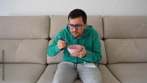 Man eating in the sofa after dental procedure with difficulty to open the mouth