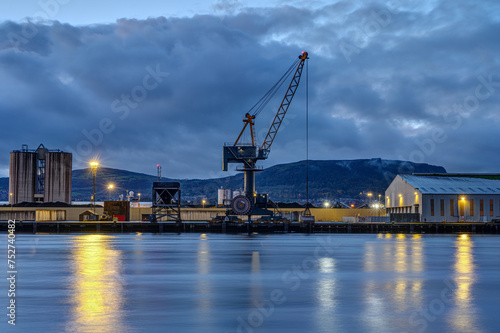 A loading crane and storehouses in the port of Belfast at twilight © elxeneize