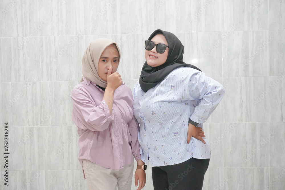 The happy expression of two Asian Indonesian hijab-wearing women wearing white and pink clothes