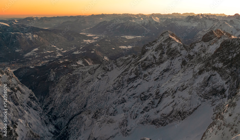View from the German highest point called Zugspitze mountain down to the Bavarian village Garmisch Partenkirchen and Grainau during sunrise phase