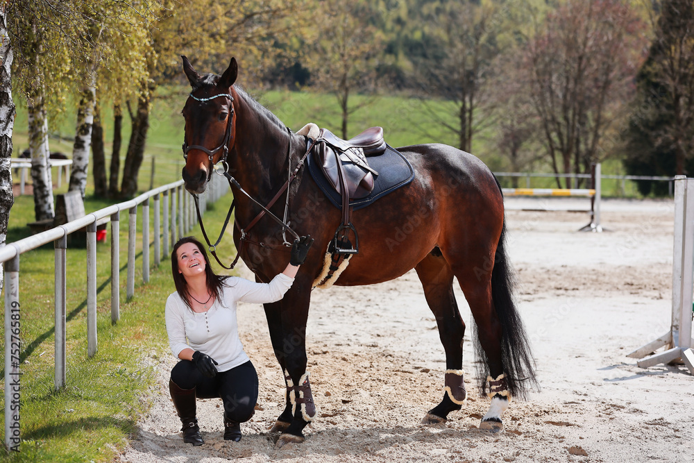 Young Frtau rider with brown long hair in portrait with her horse on the riding arena. Young Frtau rider with brown long hair in portrait with her horse on the riding arena.