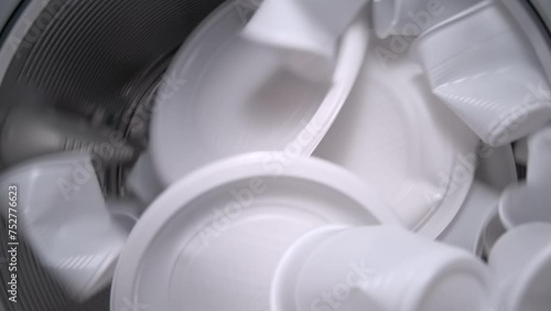 Inside view of the washing machine drum with white food plastic, close-up of the drum during the spin cycle. Concept of recycling plastic and ecology. Plastic waste. photo