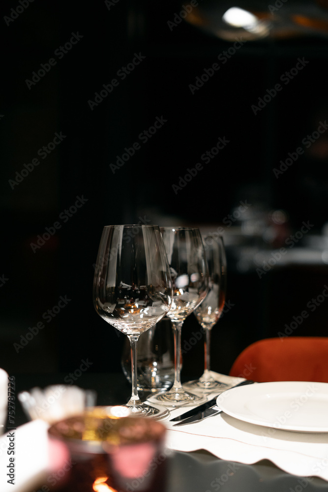 Table settings for fine dining with glassware, dark blurred background. For events, weddings, birthdays and celebrations. Table settings for fine dining with glassware, dark blurred background. For events, weddings, birthdays and celebrations.