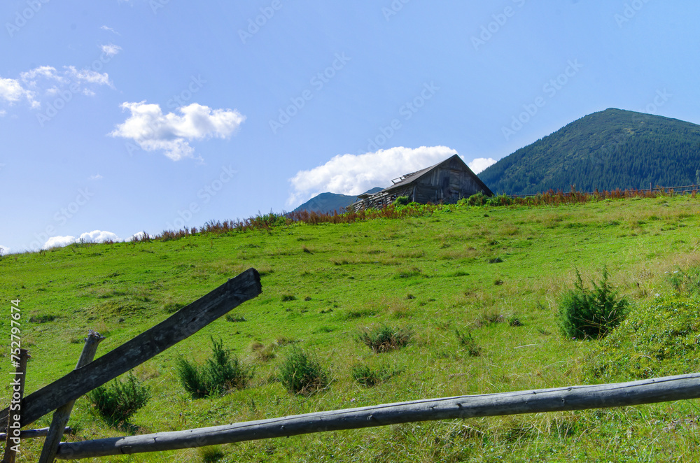 an old wooden lodge on a hill against a background of mountains. rural landscape
