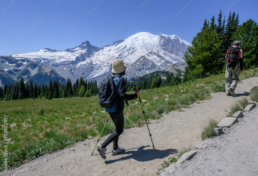 Two people hiking Sunrise Trail at Mount Rainier National Park in summer. Washington State.